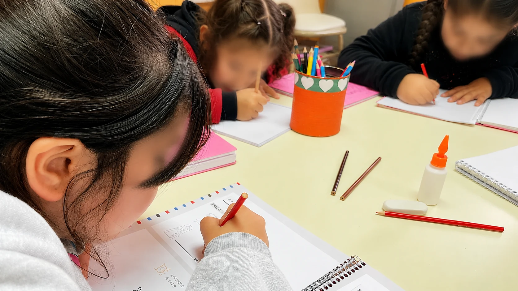 Una chica completa con lápiz una consigna de escritura en el taller de palabras